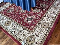 Corner of rug showing red field with ivory and gold floral border