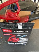 Red Toro Ultra Plus electric blower and original product box with labels showing power and features.