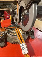 Full view of saw mounted on red workbench showing blade guard, base, fence and scale