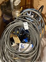 Air compressor with coiled air hoses and other accessories piled on top.