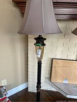 Full view of floor lamp showing metal base, glass accents, and beige fabric shade with tag reading '56 Floor Lamp'.