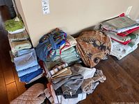 Stack of folded cloth towels and napkins including blue, green, beige, and patterned fabric linens.