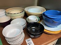 Full set of vintage mixing bowls, soup bowls, ramekins showing various colors, sizes and styles including blue, cream, black, white ribbed and floral designs.