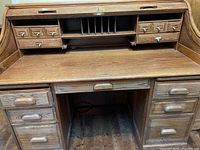 Front view of roll top desk showing multiple drawers and compartments with brass hardware.