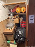 Photo showing stacked boxes with a Santa sleigh decoration on top, large decorative pumpkins, and a metal wire Christmas tree decoration.