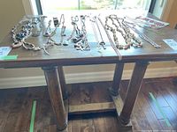 Full top shot of the wooden side table with various jewelry pieces laid out on the surface, showing tabletop scratches