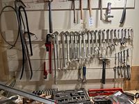 Wide view of tools displayed on wall, showing wrenches, hammers, sockets and pipe wrenches.