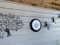 Wall installation of metal tree art, round clock, and two metal butterfly sculptures