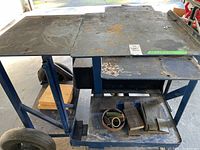 Front view showing steel top surface and lower shelf with metal blocks and ring