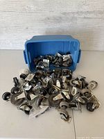 Overview photo showing a blue storage tote tipped on its side with many caster wheels spilling out on a white surface, against a wood panel background.