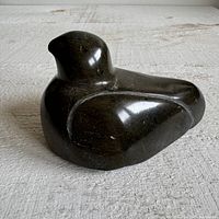 View of the sitting bird soapstone carving from a side angle showing the detailed shape and surface condition.