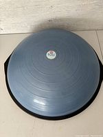 Top-down view of the blue dome and black base of the Bosu balance trainer showing its circular design and logo at center.