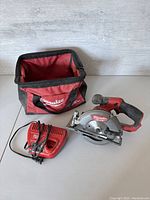 Circular saw body, charger and bag laid out on white surface