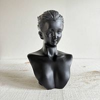 Front view of the black plastic female bust jewelry display on a neutral background.
