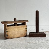 Front and side view of the light wooden butter press box with dark wooden press tool on right.