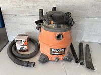 Ridgid blower vac with flexible hose and orange box accessory on the side, also shows main unit.