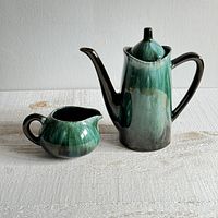 Photo of the full set showing kettle and creamer side by side on a textured white cloth.