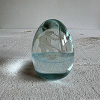 Front view of the glass paperweight with visible etched fisherman design and bluish detail near base
