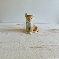 Front view of the porcelain lion cub figurine showing its sitting posture and facial details.