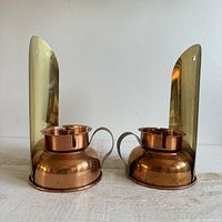 Front view of the pair of vintage brass and copper candle wall sconces with arched backplates and copper candle holders.