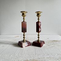 Pair of vintage candlestick holders, brass and red/cranberry with white stone, front view showing overall condition and materials.