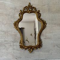Full view of vintage gold tone ornate wall mirror featuring floral and scrollwork decorative frame