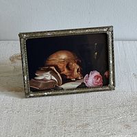 Front angled view of the vintage inlay frame with the still life print showing skull, book, flower, and goblet inside.