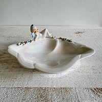 Front angled view showing the opalescent glaze, elf pixie figure with blue accents, and floral trim.