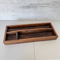Front angle of the wooden vintage saw tool organizer on a white surface with wood panel wall background.