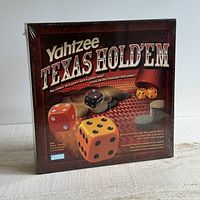Front view of unopened Yahtzee Texas Hold 'Em dice game in original shrink wrap with some wear on plastic.