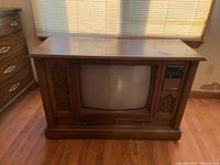Full front view of the classic vintage console television in a wooden cabinet showing the CRT screen and speaker wood grille.