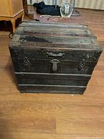 Front and top view of the old wooden trunk showing metal reinforcements and central lock with side clasps.