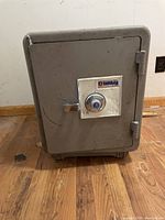 Full view of the Sentry safe showing front door, handle, and general condition on wooden floor.