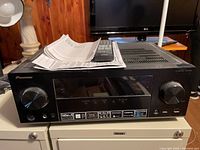 Front top view of Pioneer multi-channel receiver with remote and manuals lying on top.