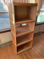Full view of the handmade hardwood shelving unit showing its four shelves and natural wood finish in a well-lit room.