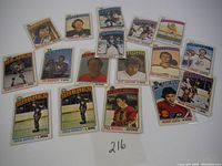 Full view of 17 hockey cards spread out on white background showing various players and teams from 1976 NHL cards.