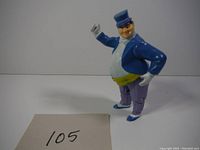 Front and side view of the Penguin figure showing blue jacket, green vest, purple pinstriped pants, purple top hat.