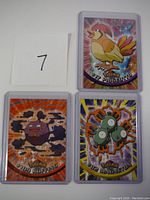 Three encapsulated Pokemon cards displayed with a numbered note '7' beside them.