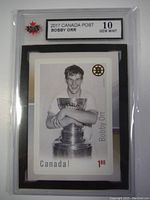 Photo of a 2017 Canada Post Bobby Orr commemorative stamp with Gem Mint 10 grading, showing Bobby Orr holding the Stanley Cup with a denomination of 1.80.