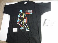 Full view of black vintage XL T-shirt featuring colorful hockey player graphic and Memorial Cup text, alongside a CD and paper inserts.