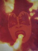 Close-up of album cover art featuring a fiery explosion with a band member's face painted with classic KISS makeup.