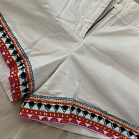Close-up of the front zipper and embroidered hem detail showing multicolor geometric stitching in red, pink, black, blue, and orange.