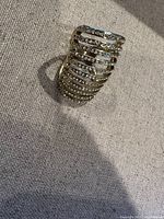 Gold-tone ring with horizontal bands and small rhinestones, top-angle view showing detail and sparkle.