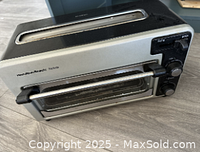 Front angle view showing stainless steel finish, glass door with handle, and upper toast slot.