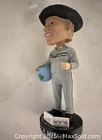 Front and side views of Dick Rutan bobblehead figurine in flight suit holding globe, standing on a Mojave Air and Space Port base