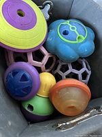 Top-view of assorted dog puzzle toys in a storage bin showing various shapes and colors
