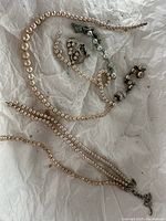 Multiple pearl necklaces and bracelets laid out on tissue paper showing variety of sizes and clasp types