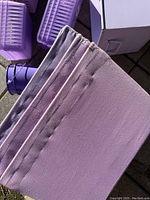 Close-up of purple foldable fabric baskets stacked together showing material texture and label holder details.