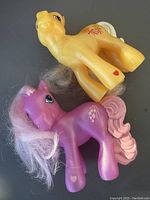 Two My Little Pony Happy Meal toys, yellow and purple ponies, displayed side by side showing full body and hair