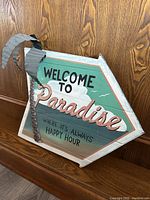 Front view of the wooden arrow sign showing the text and full design with attached palm tree detail.